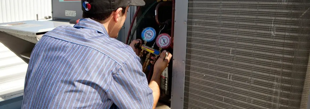 HVAC technician servicing a condenser unit in Blackstone