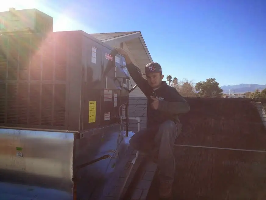 HVAC technician performing Air Duct Cleaning on a rooftop unit in Blackstone